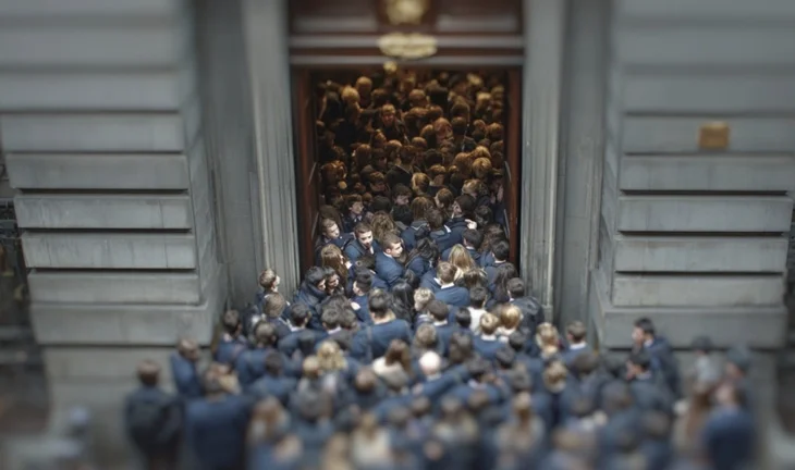 a mass of young people in suits trying to get through the door of a bank in London 