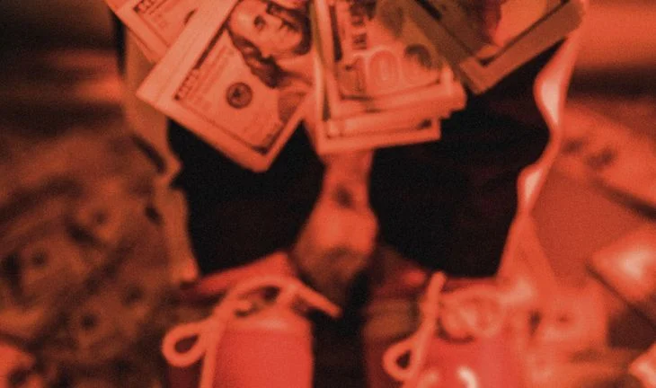 Holding $100 bills in red light 