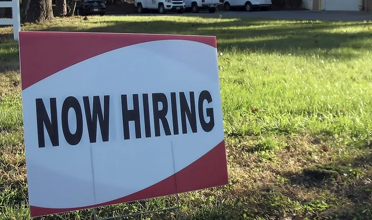 a sign that says now hiring 