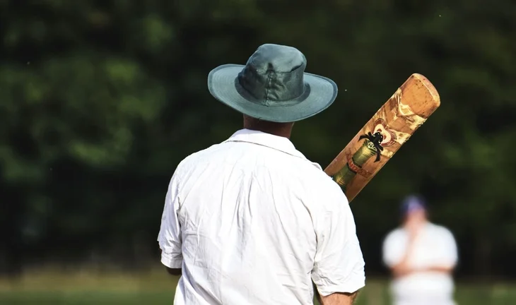 a man in a hat holding a cricket bat